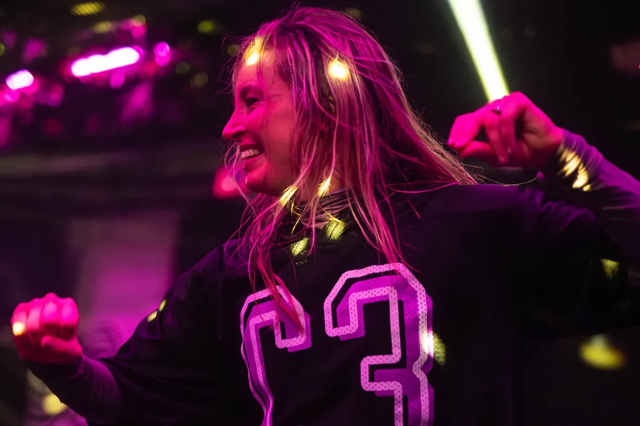 An adult dancer in a C3 jersey grinning under the lights
