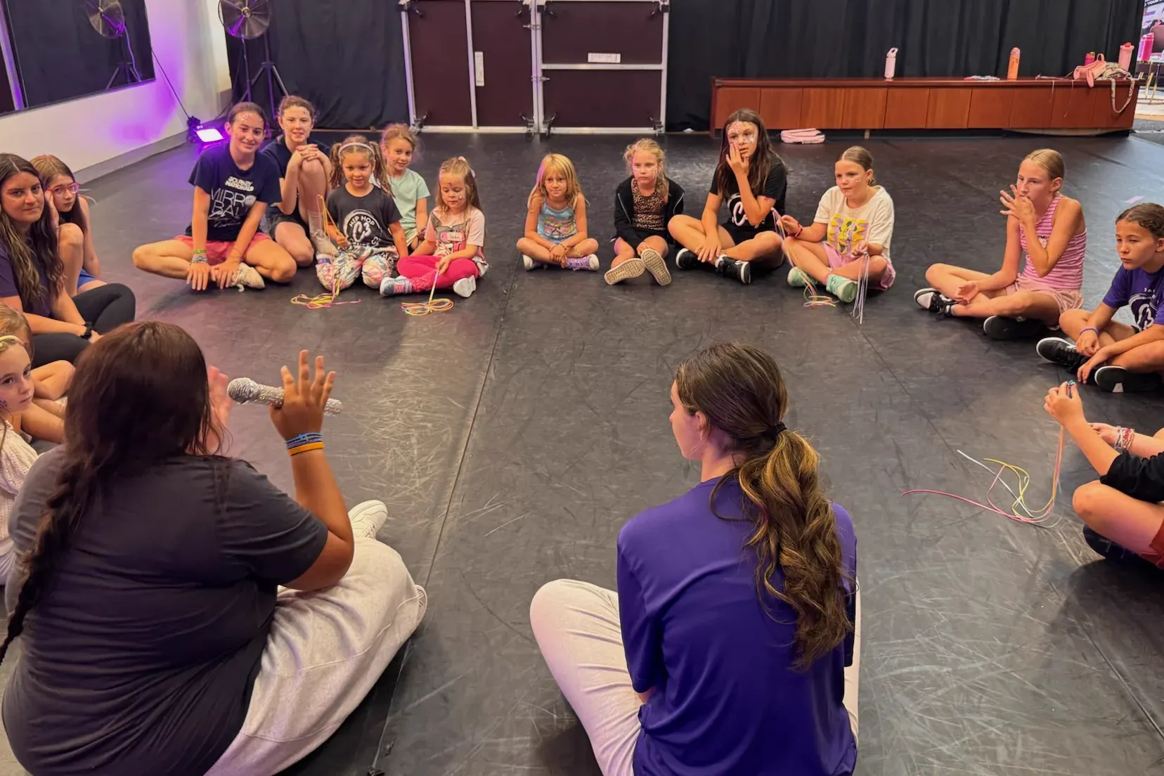 C3 coaches and campers sitting in a circle on the studio floor talking together