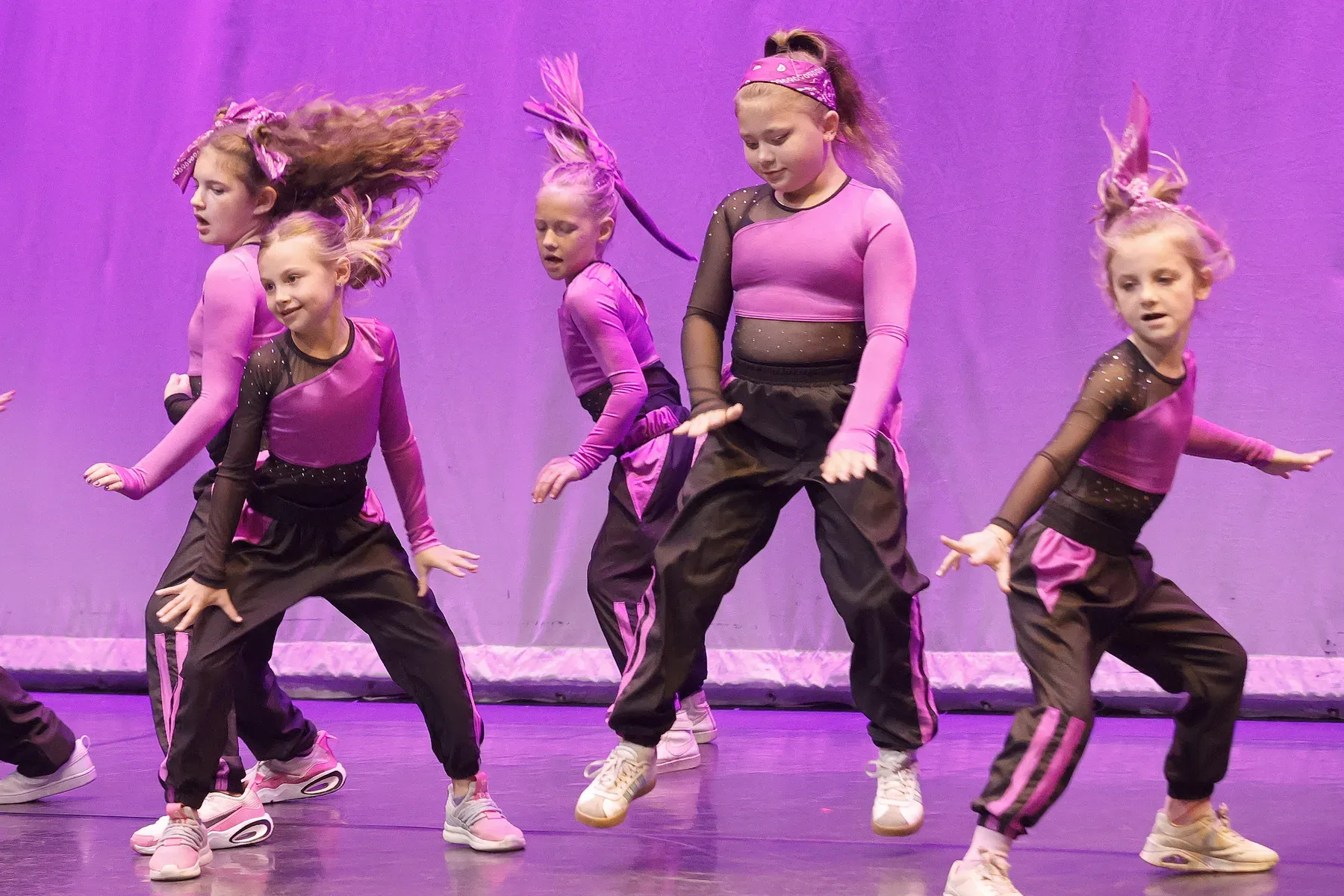 C3’s youngest dancers hitting a pose together under purple stage lights