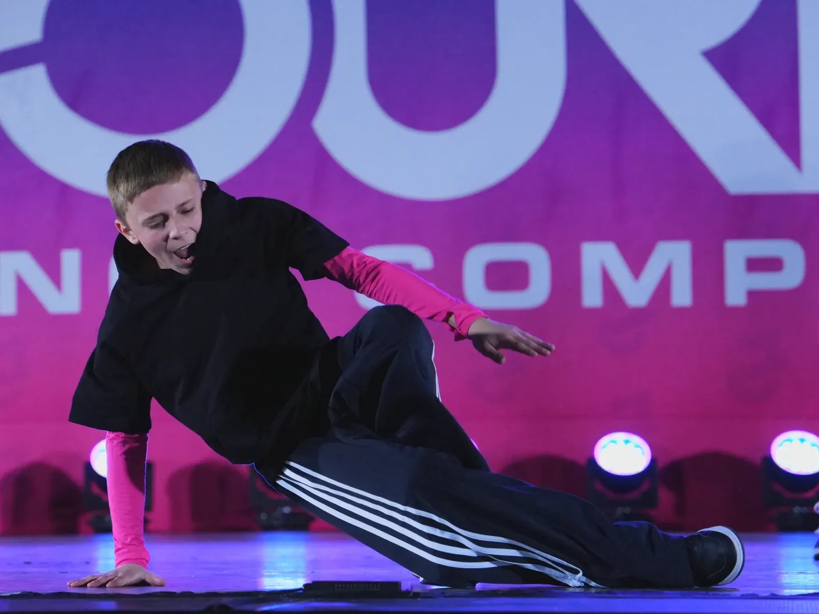 A young breaker holding a freeze on a competition stage