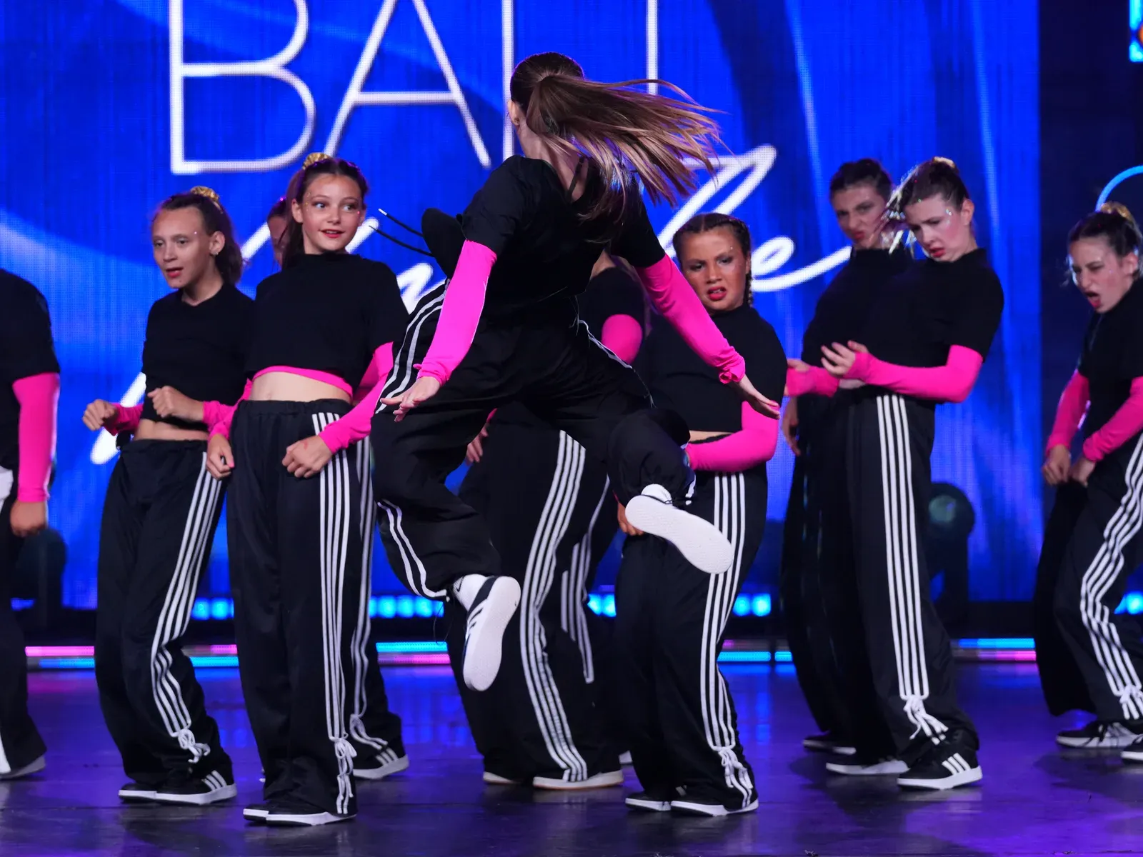 A C3 dancer leaping mid-routine as her team hits the count behind her